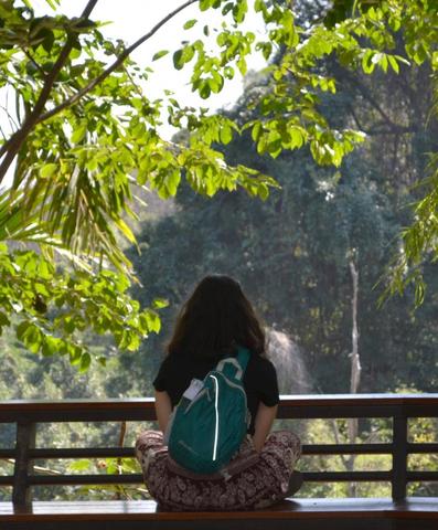 A student sits and stares at a waterfall